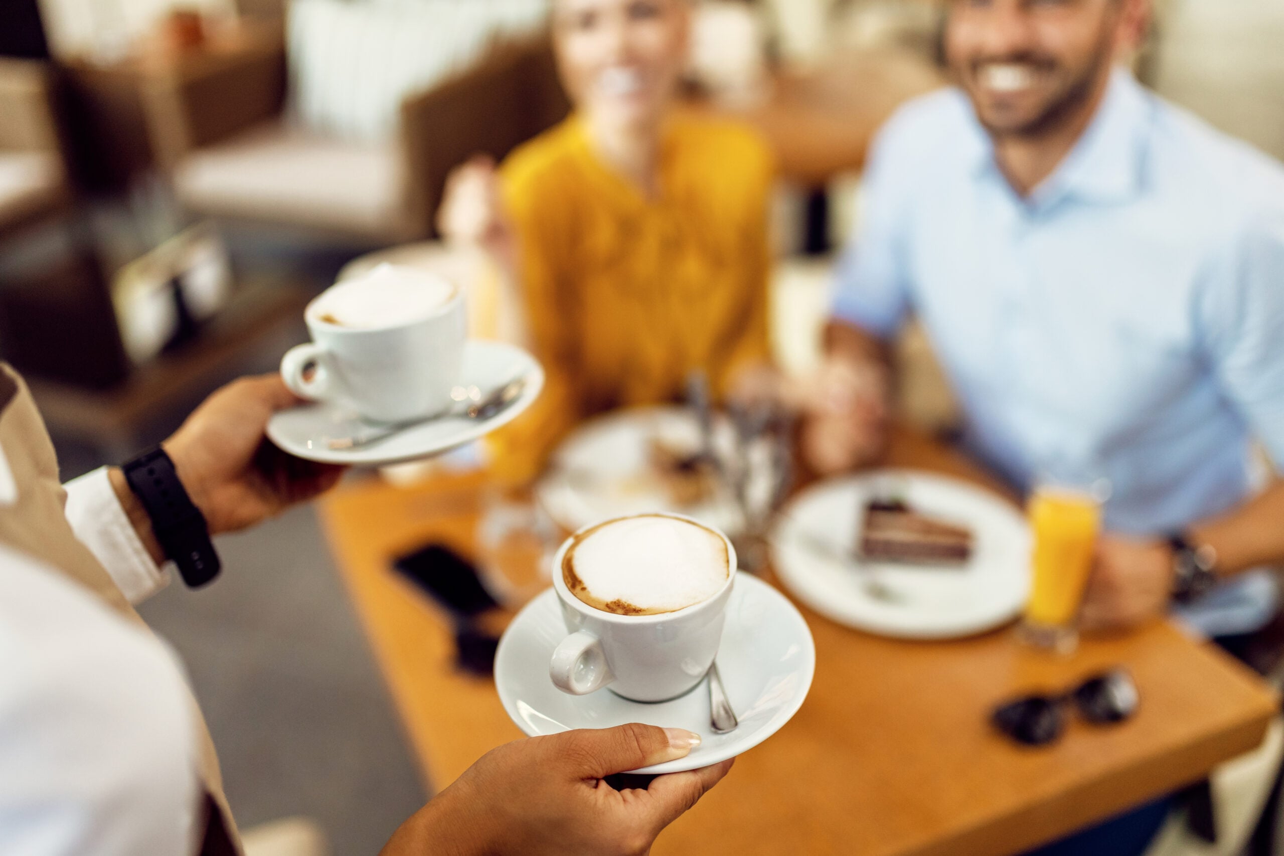 servitris kommer med två kaffekoppar till ett bord